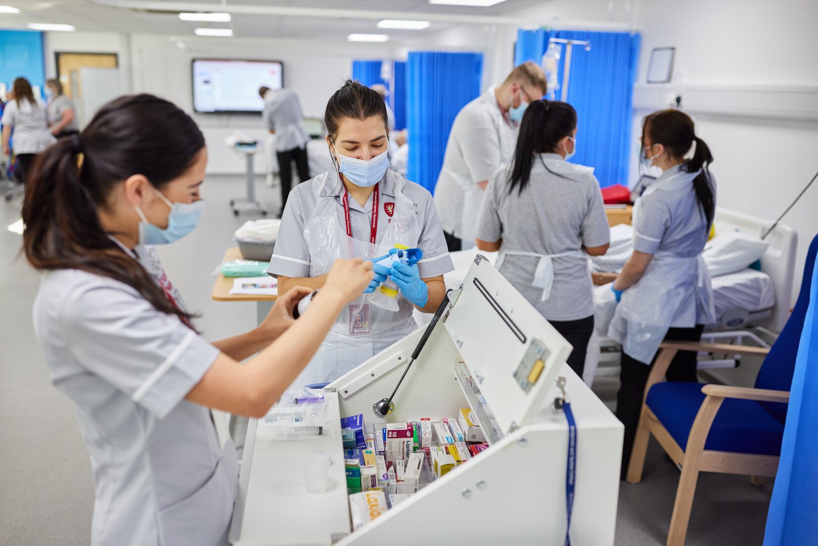 Student nurses working around a bed and dispensing cabinet in the Clinical Skills and Simulation Centre